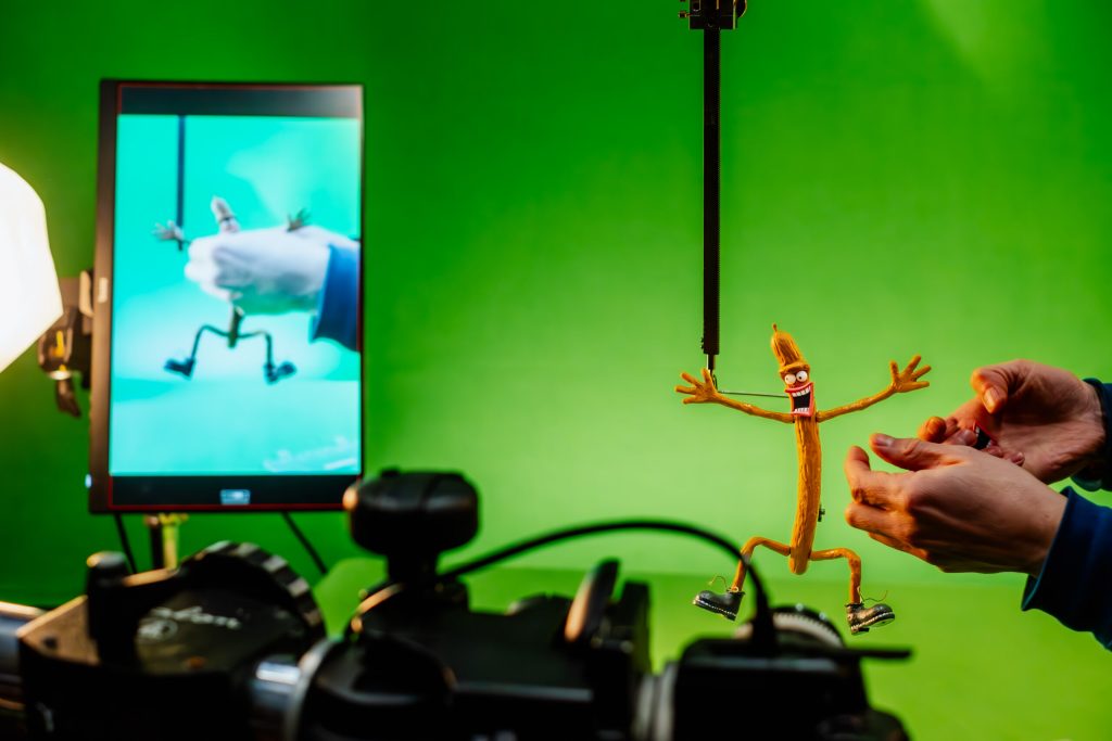Animator adjusts the Peperami character puppet for a stop-motion food & drink commercial on a green screen set.