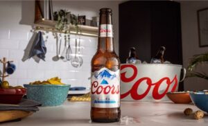 A chilled bottle of Coors beer on a kitchen counter with snacks, showcasing high-quality commercial work by Dead Pixel Films, a social media video production company in the UK.