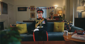 A man in a British military dress uniform sitting on a sofa with tea and biscuits, showcasing a creative project by Life Media UK, a social media video production company.