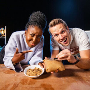 Two presenters reacting to food on a wooden table, showcasing engaging content by Studio 91 Media, a social media video production company in the UK.